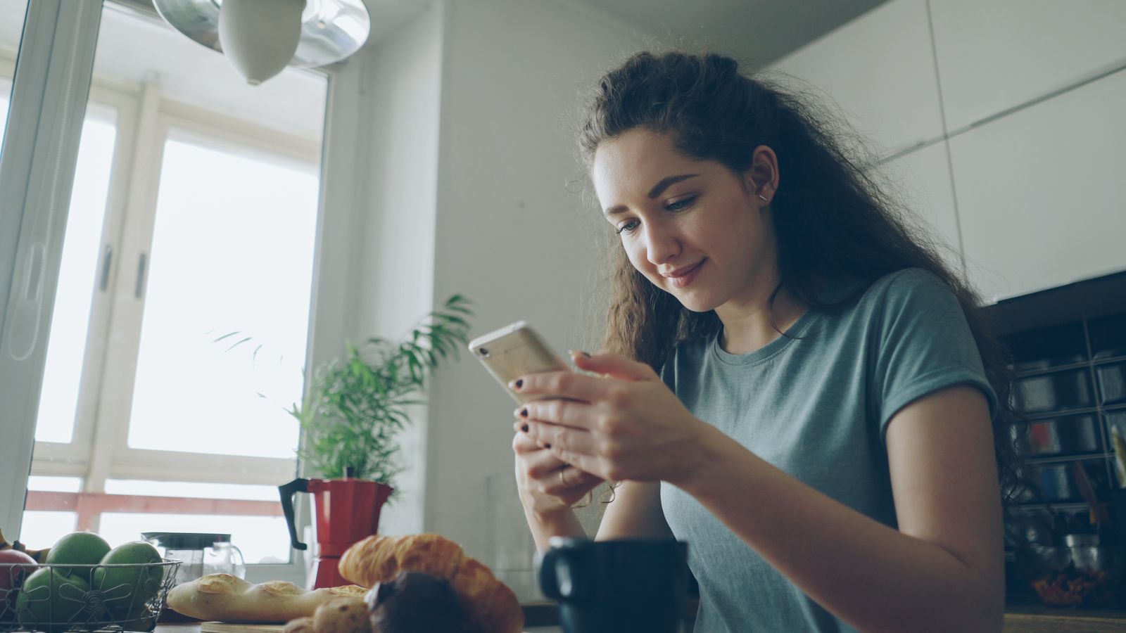 Homeowner in a bright kitchen, smiling at her phone while choosing what to have repaired